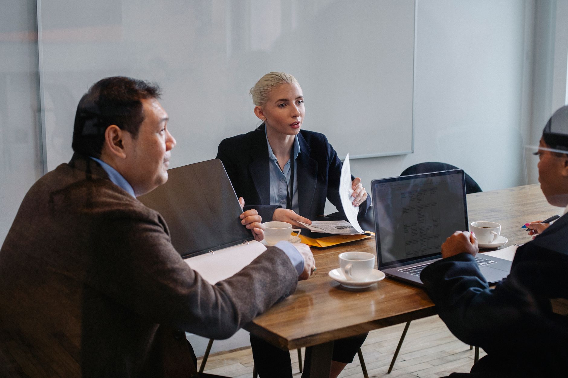 Colleagues in business attire reviewing documents together at a conference table with a laptop